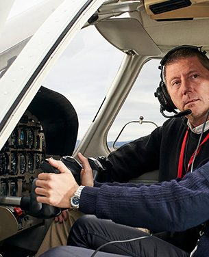 Dois homens no cockpit de um pequeno avião, concentrados em seus instrumentos de voo.